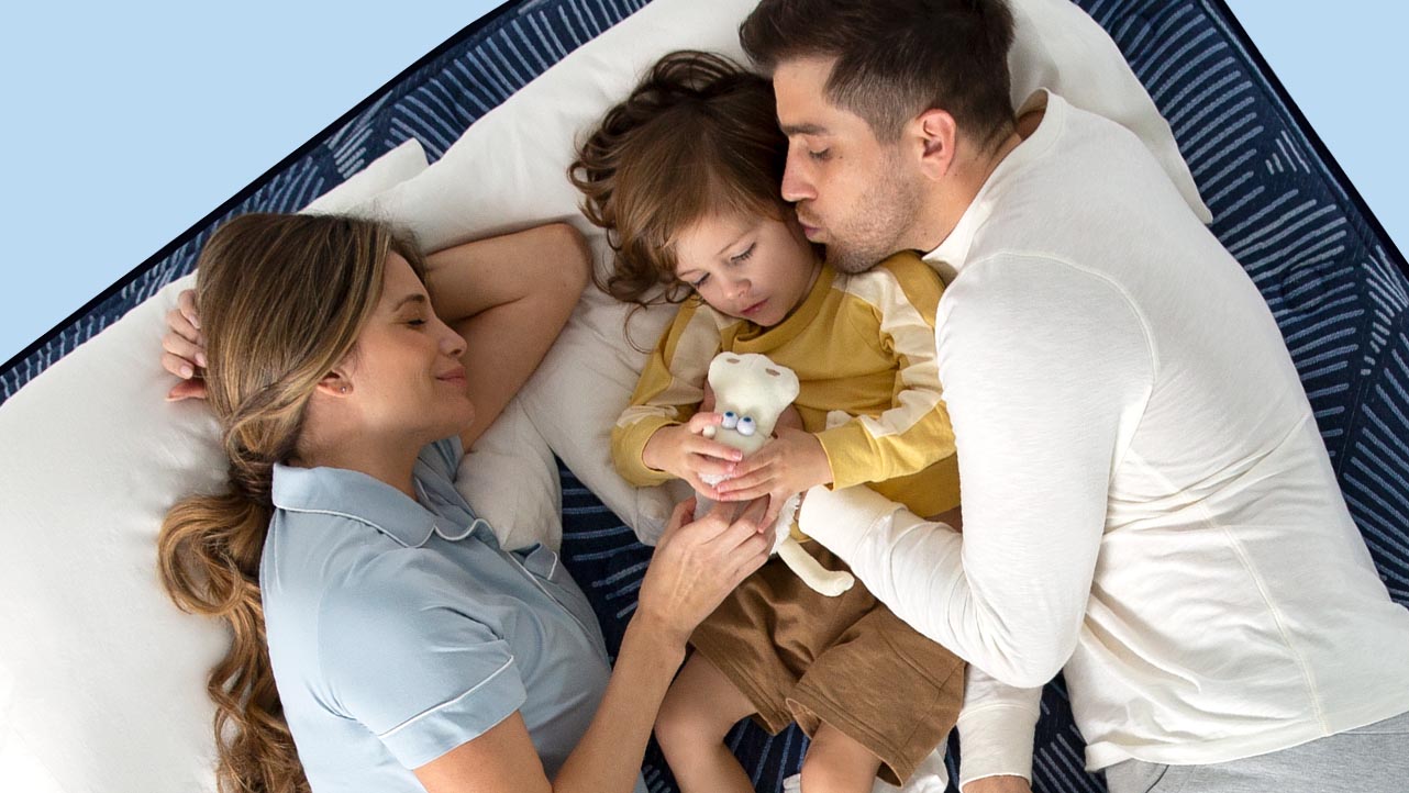 A couple with a small child sleeping on a Serta mattress in a bedroom