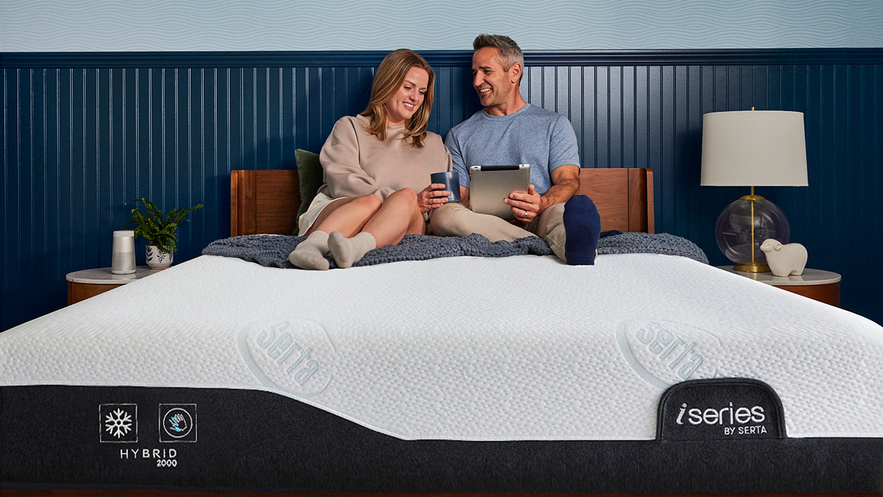 A boy sleeping on his side on a Serta mattress, snuggling with the Serta sheep