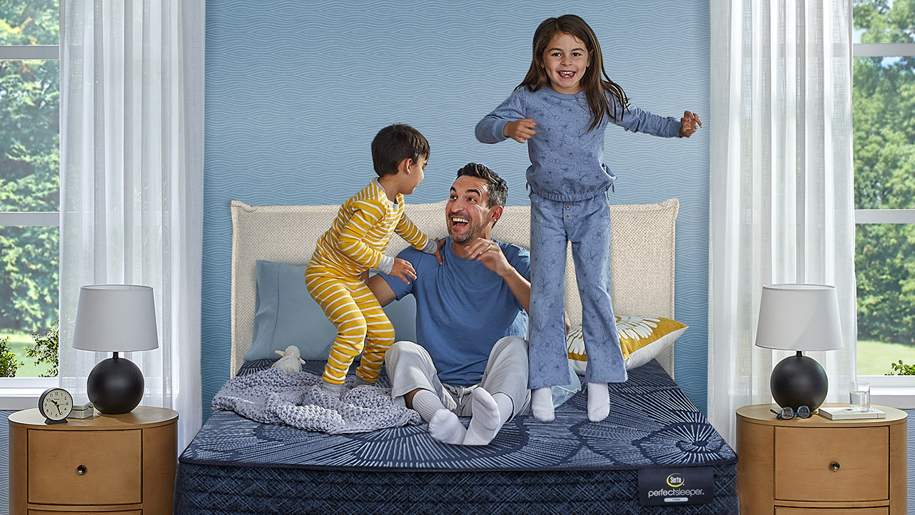 A couple with a small child sleeping on a Serta mattress in a bedroom